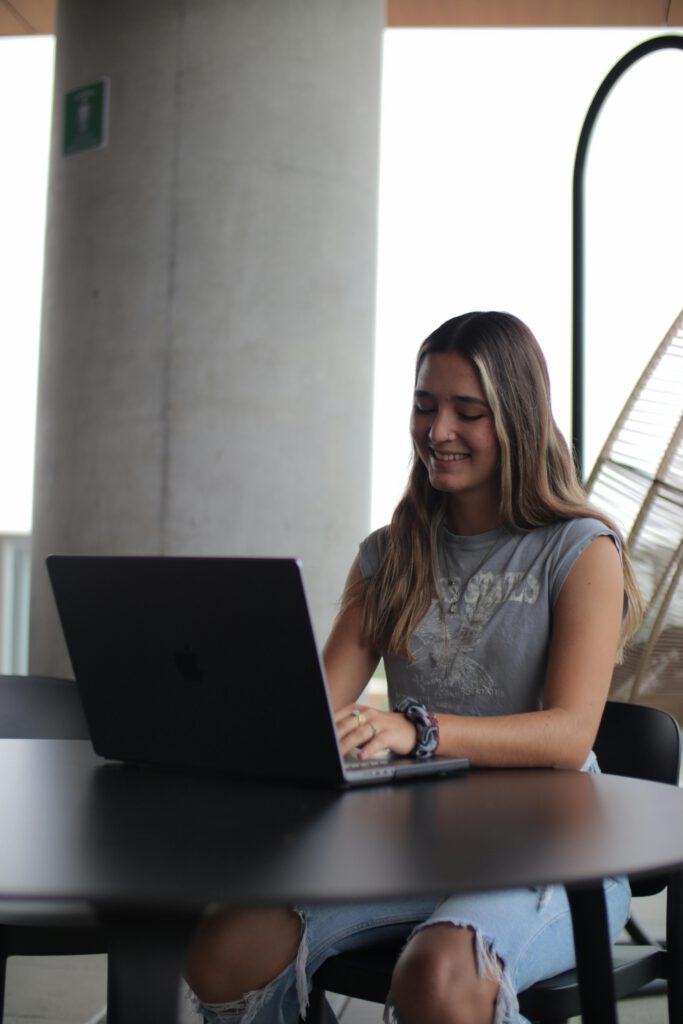 Young woman using a laptop in a modern indoor setting, focused on online study.